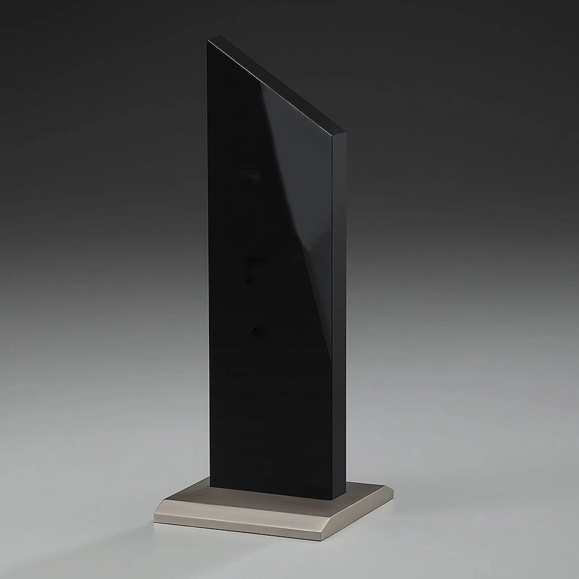 Black Monument Award – schwarze Hochglanz-Acrylglas-Stele auf gebürstetem Metallsockel, hier ohne Gravur, Seitenansicht auf grauem Hintergrund
