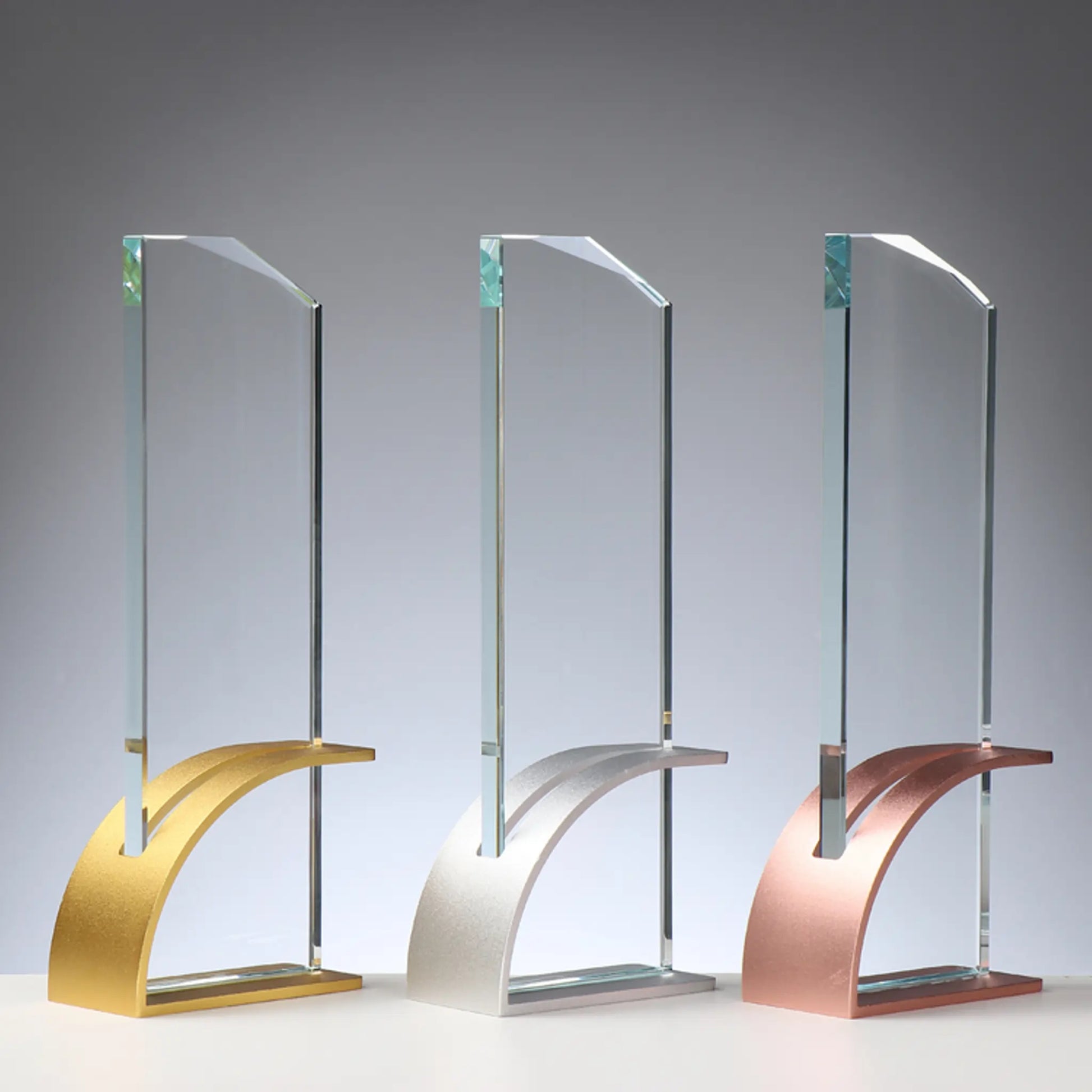 Glas-Metall Award Gold-Silber-Bronze – hohe rechteckige Glasscheibe auf geschwungenem Metallsockel in drei Ausführungen: Gold, Silber und Bronze-Farben, blank ohne Gravur, personalisierbar mit Lasergravur für Siegerehrungen und Unternehmensauszeichnungen
