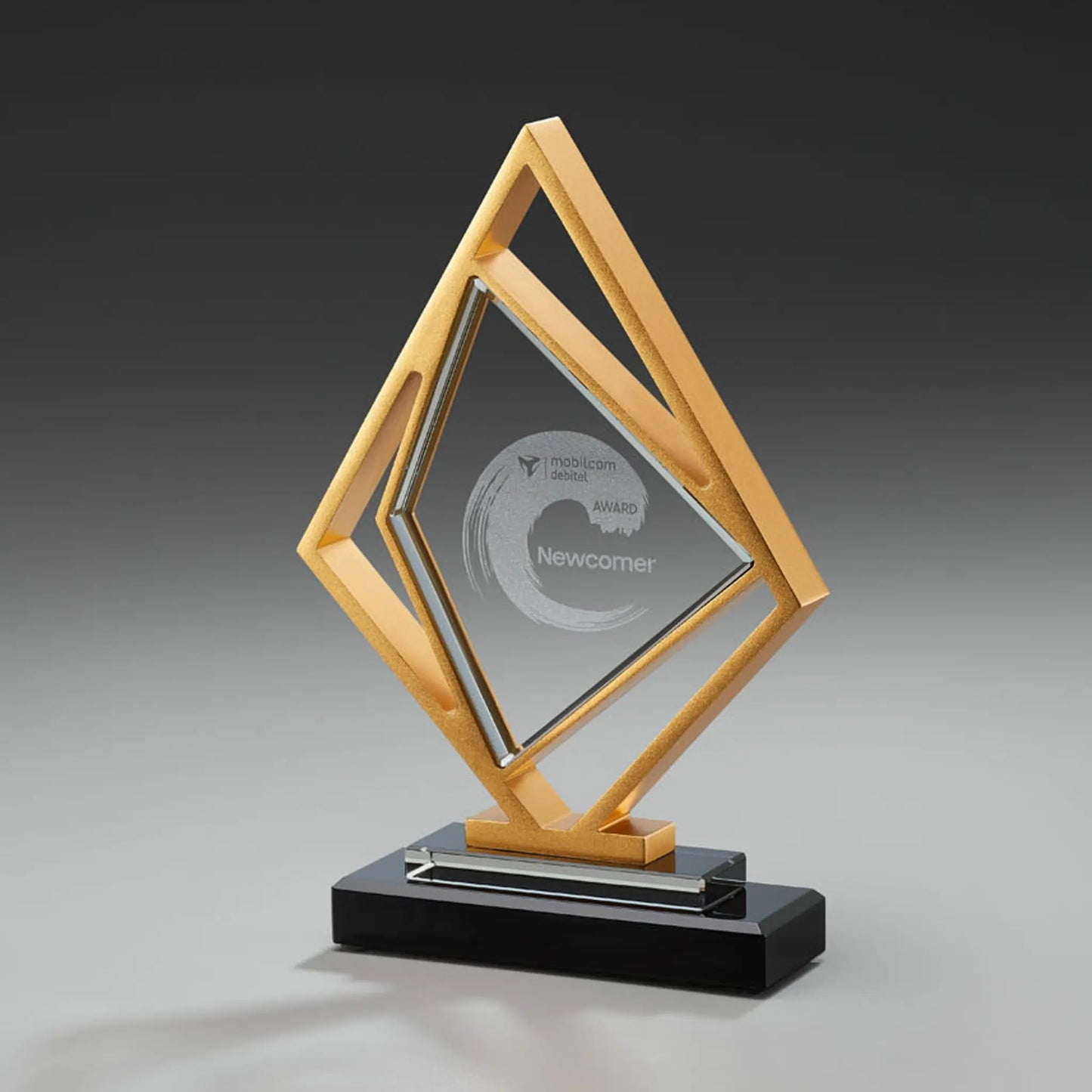 Golden Kite Award – rautenförmiger Glasblock in goldfarbenem Metallrahmen auf schwarzem Glas-Sockel, Lasergravur mit Logo und Auszeichnungstext, personalisierbar für Unternehmensauszeichnungen und Gala-Abende
