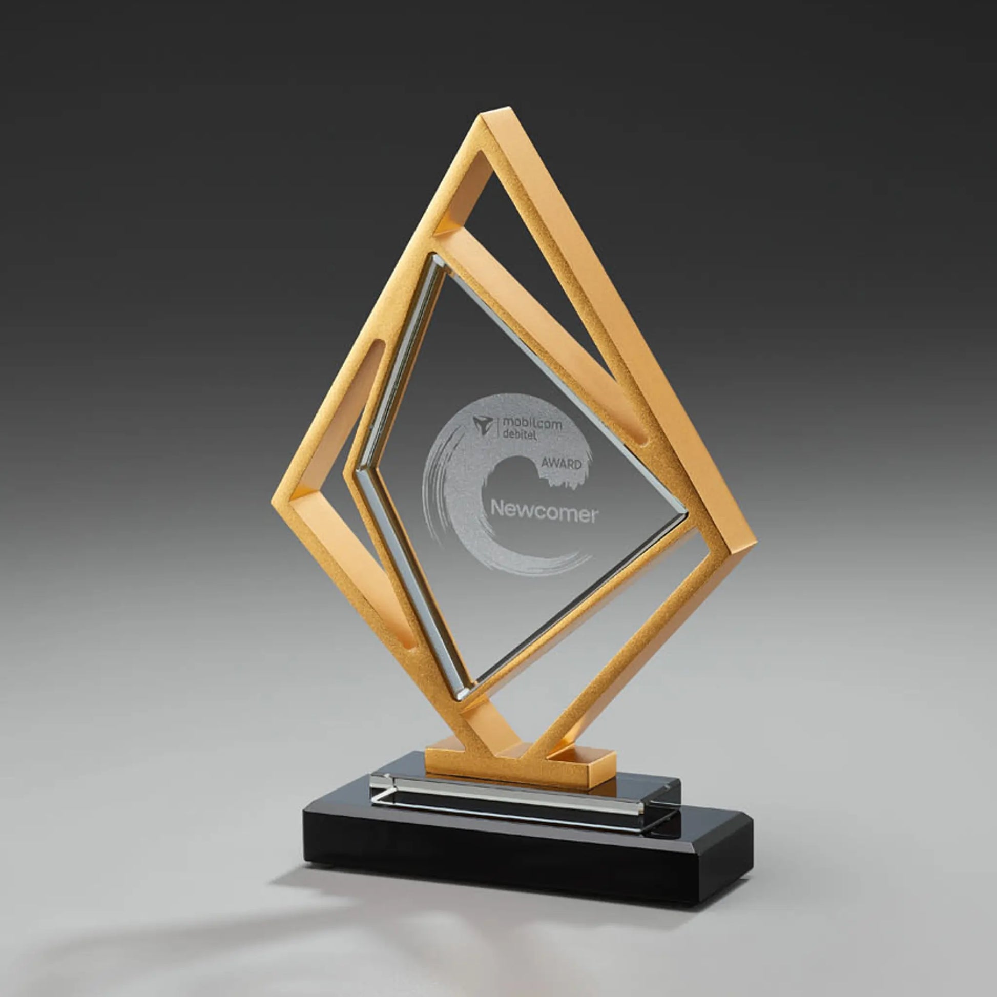 Golden Kite Award – rautenförmiger Glasblock in goldfarbenem Metallrahmen auf schwarzem Glas-Sockel, Lasergravur mit Logo und Auszeichnungstext, personalisierbar für Unternehmensauszeichnungen und Gala-Abende
