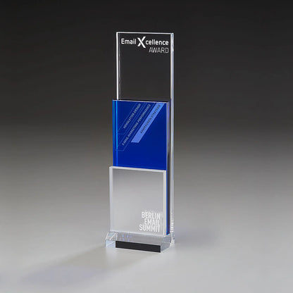 Modern Step Award mit Lasergravur und Digitaldruck: klares Acrylpanel mit Logo und Auszeichnungstitel, blaues Mittelelement mit Kategorietext, mattiertes silberweißes Element mit Veranstaltungsname, klarer Sockel 
