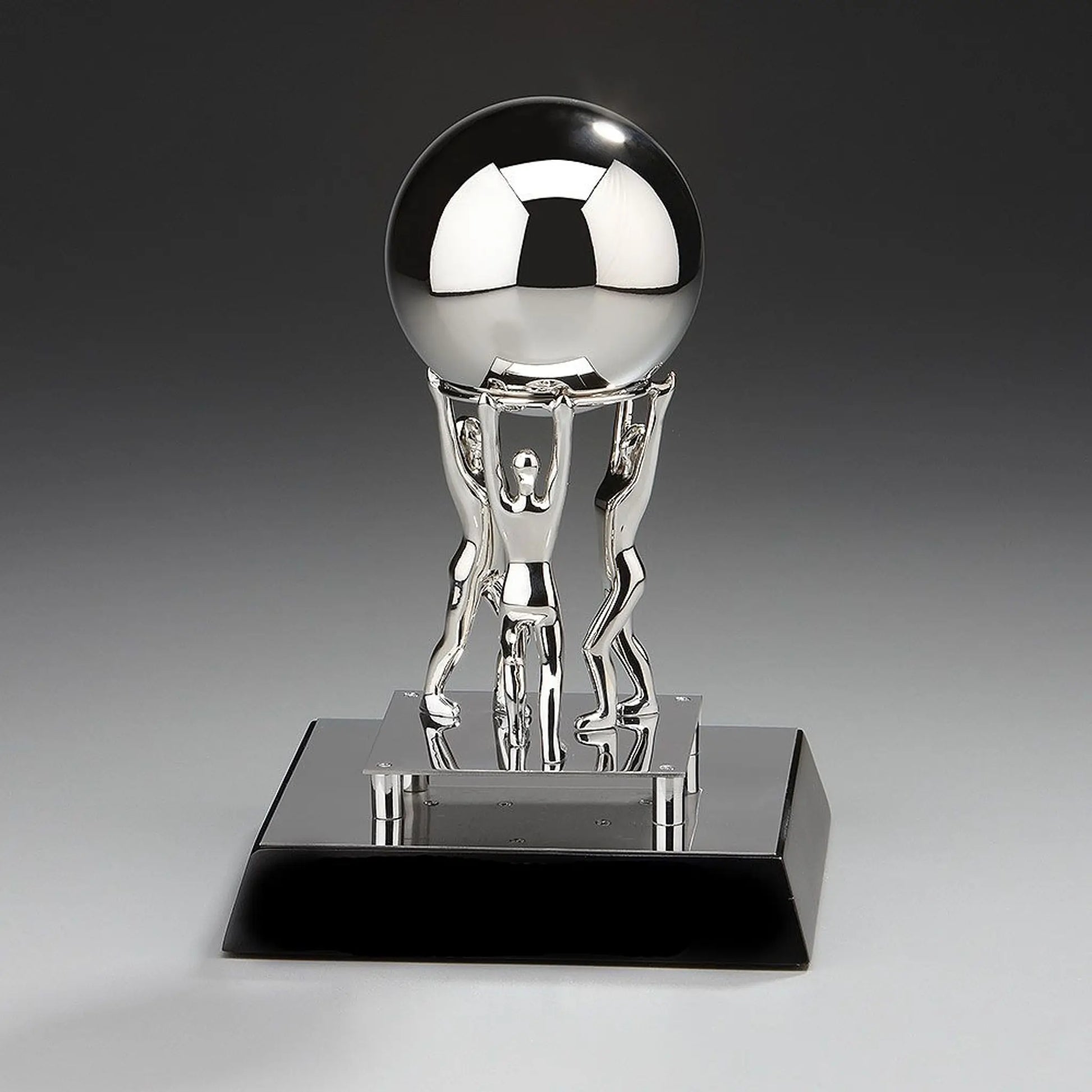 Teamwork Metal Award „Together We Can" – drei vernickelte Metallfiguren stemmen gemeinsam einen Edelstahlball, alles montiert  auf schwarzem Holzsockel, Höhe 200 mm
